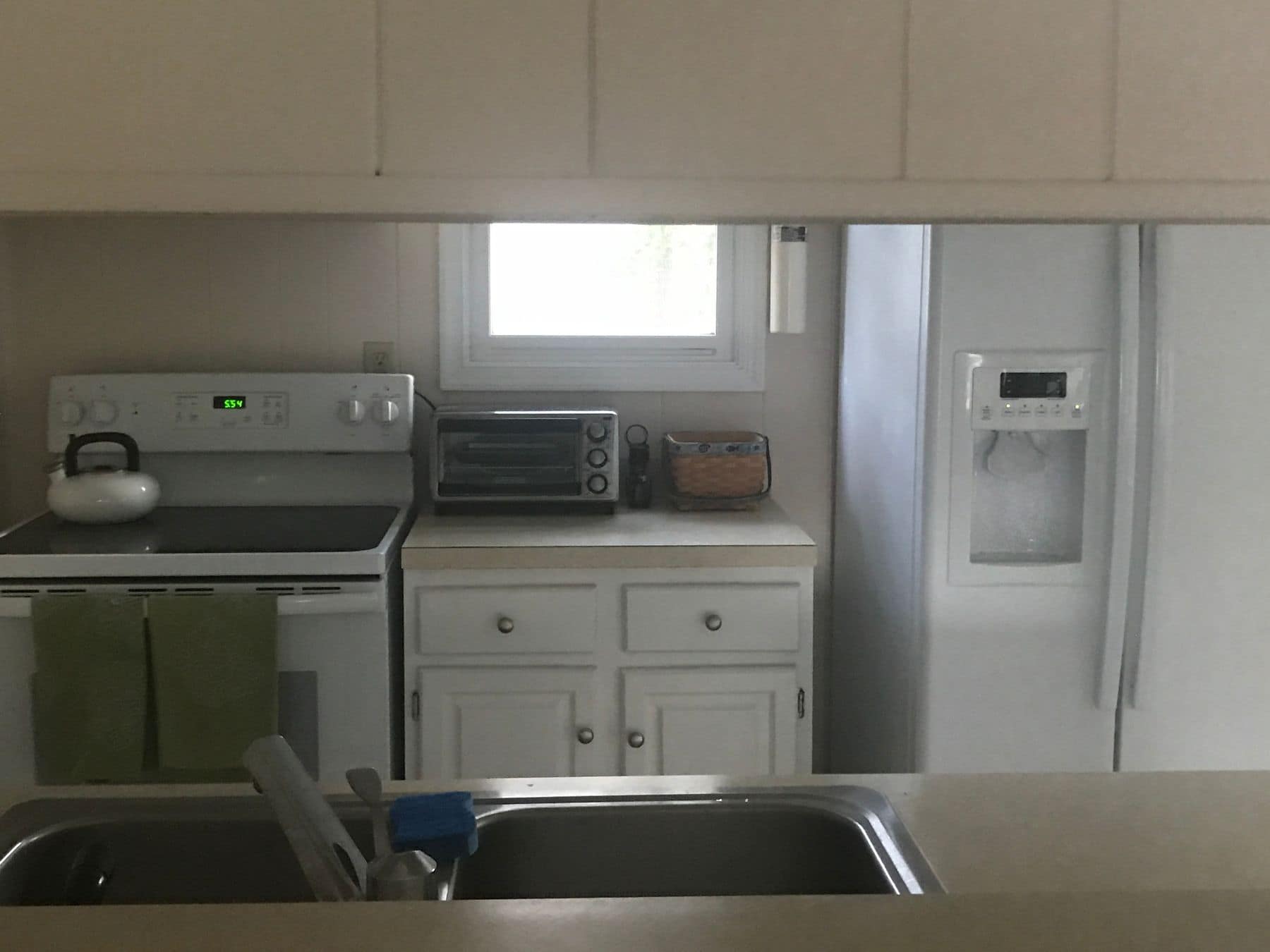 Before: the old kitchen with white appliances, seen over the sink