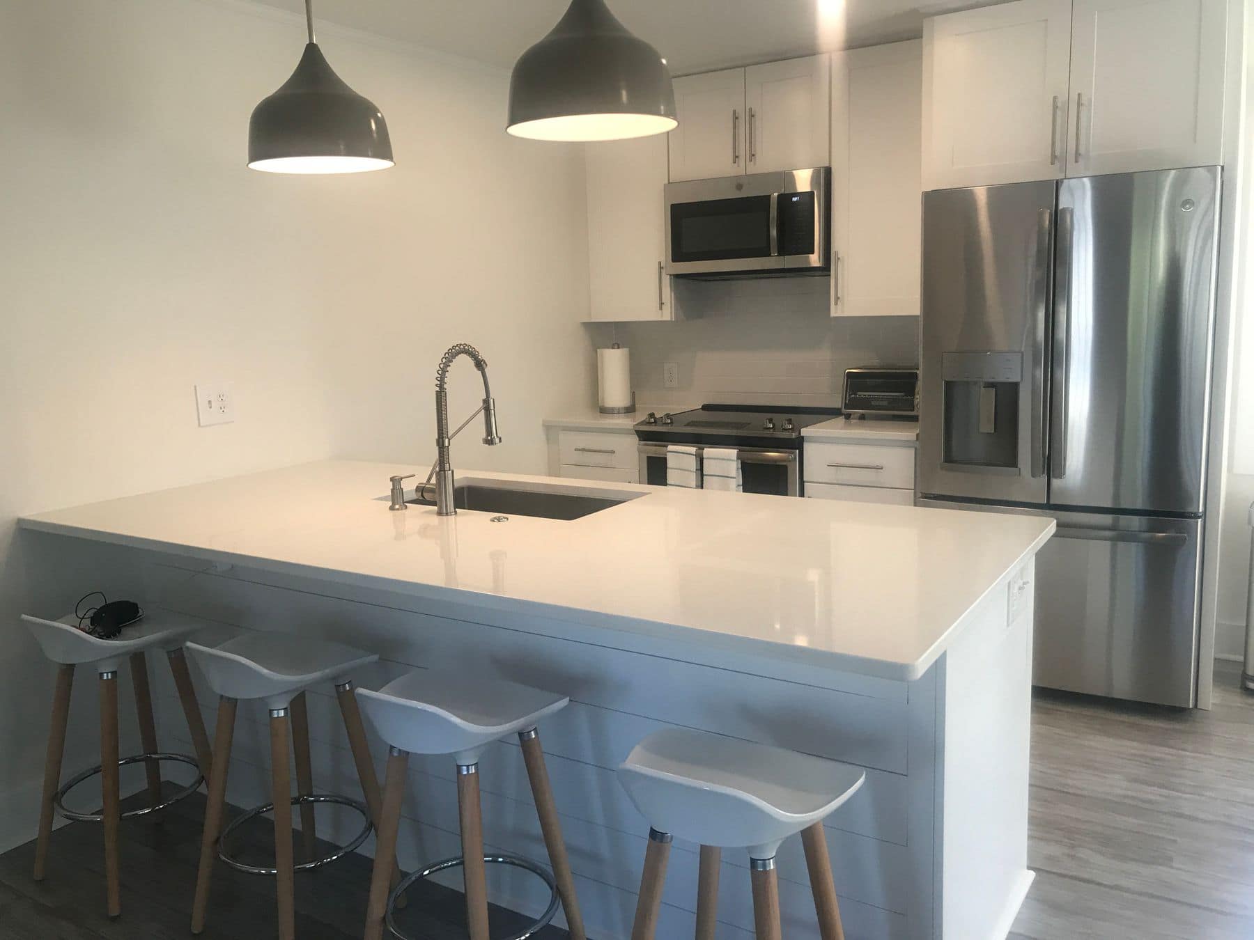 The new peninsula with white stools and dark pendant lights