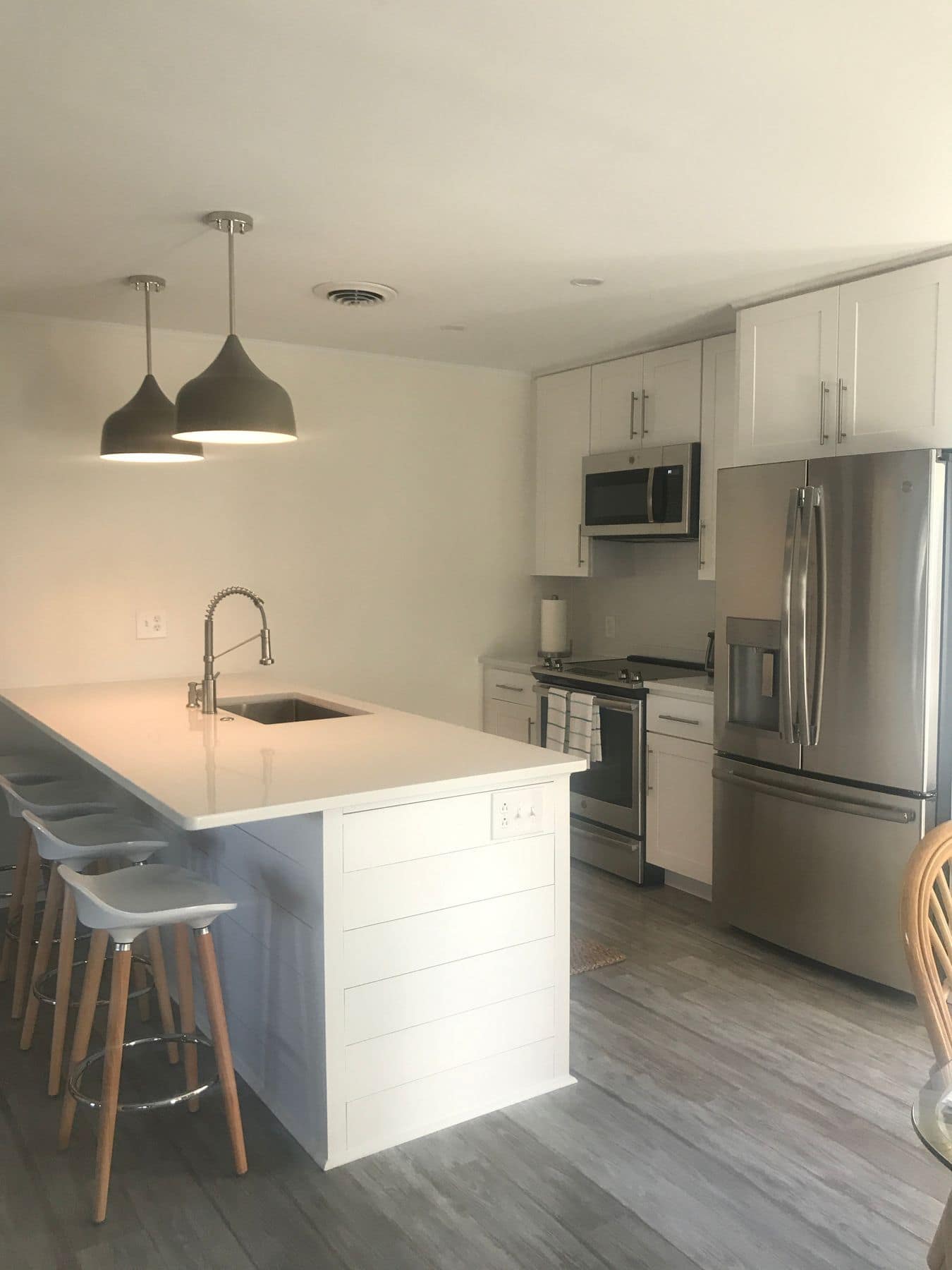 The opened kitchen: peninsula, pendants, and a stainless refrigerator