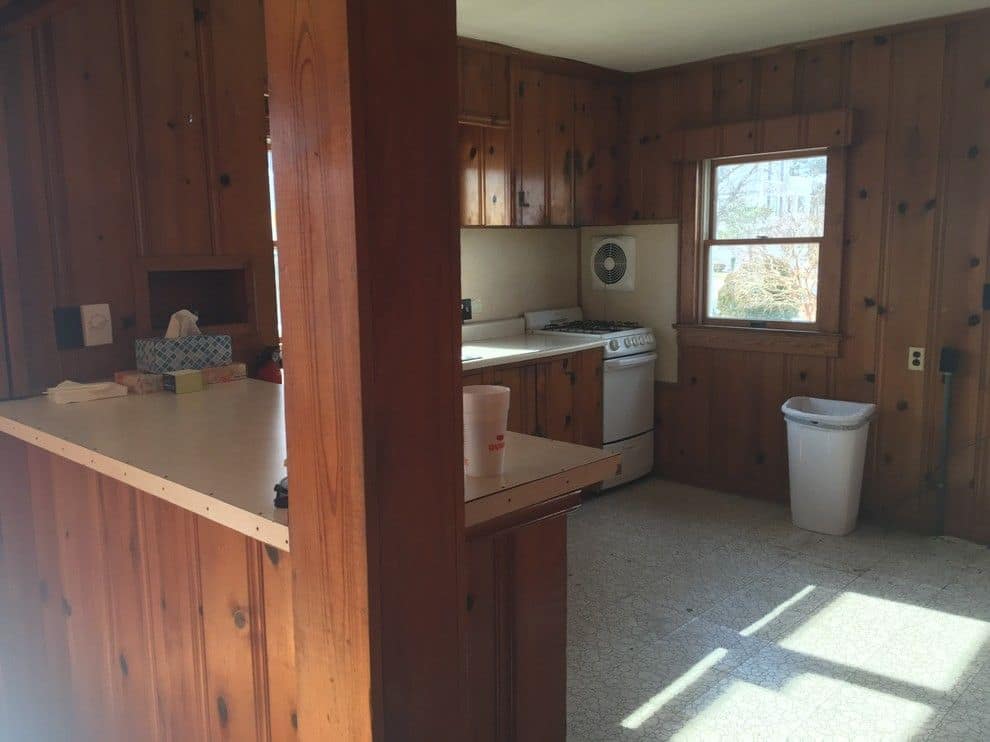 Before: the kitchen in knotty pine paneling with a post in the middle of the room