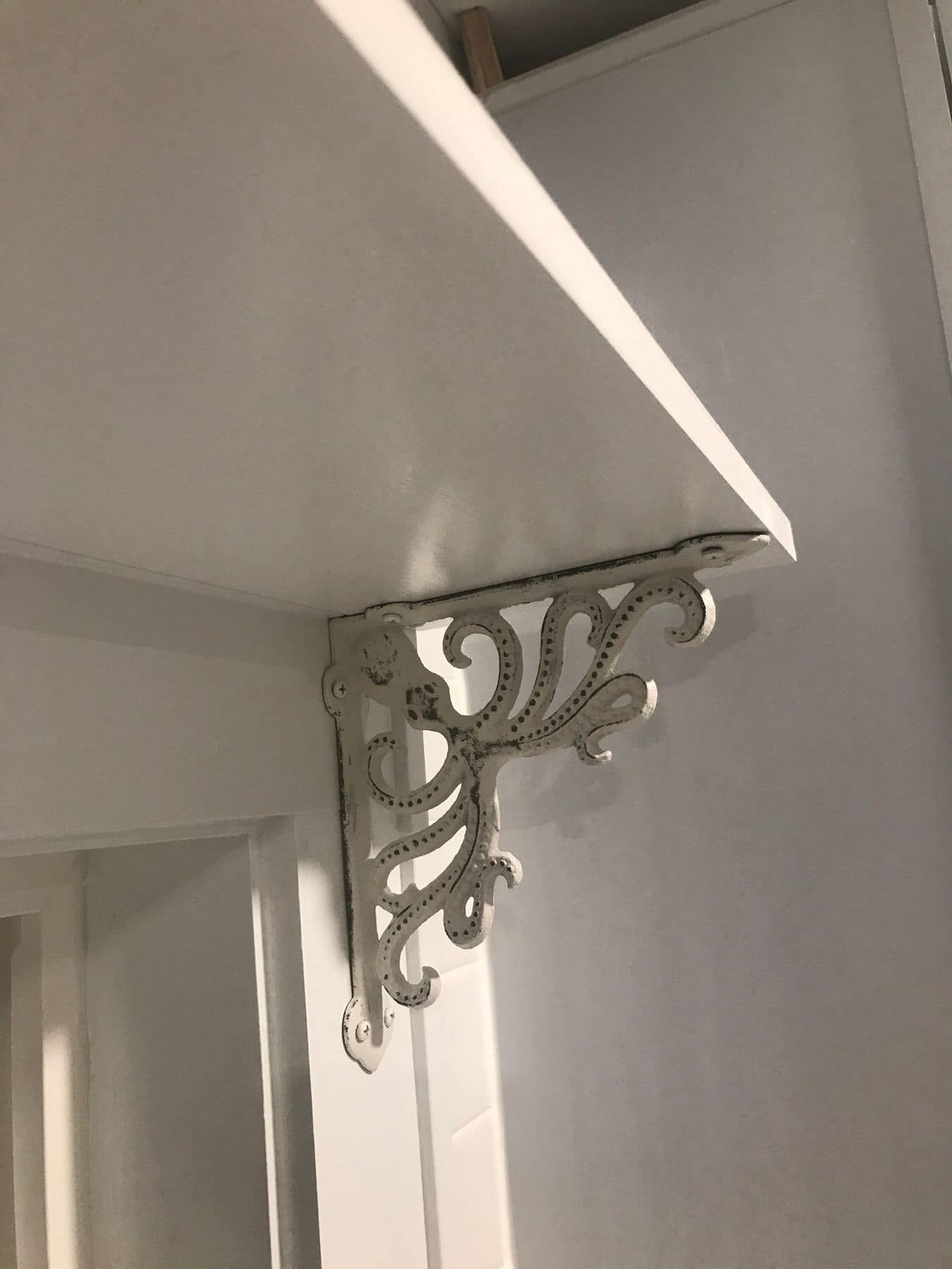 An open shelf on a decorative white bracket