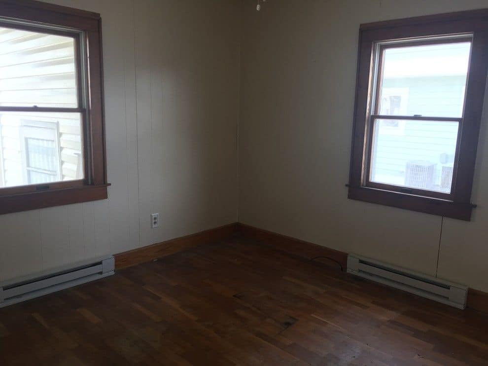Before: a bedroom with dark window trim and baseboard heaters
