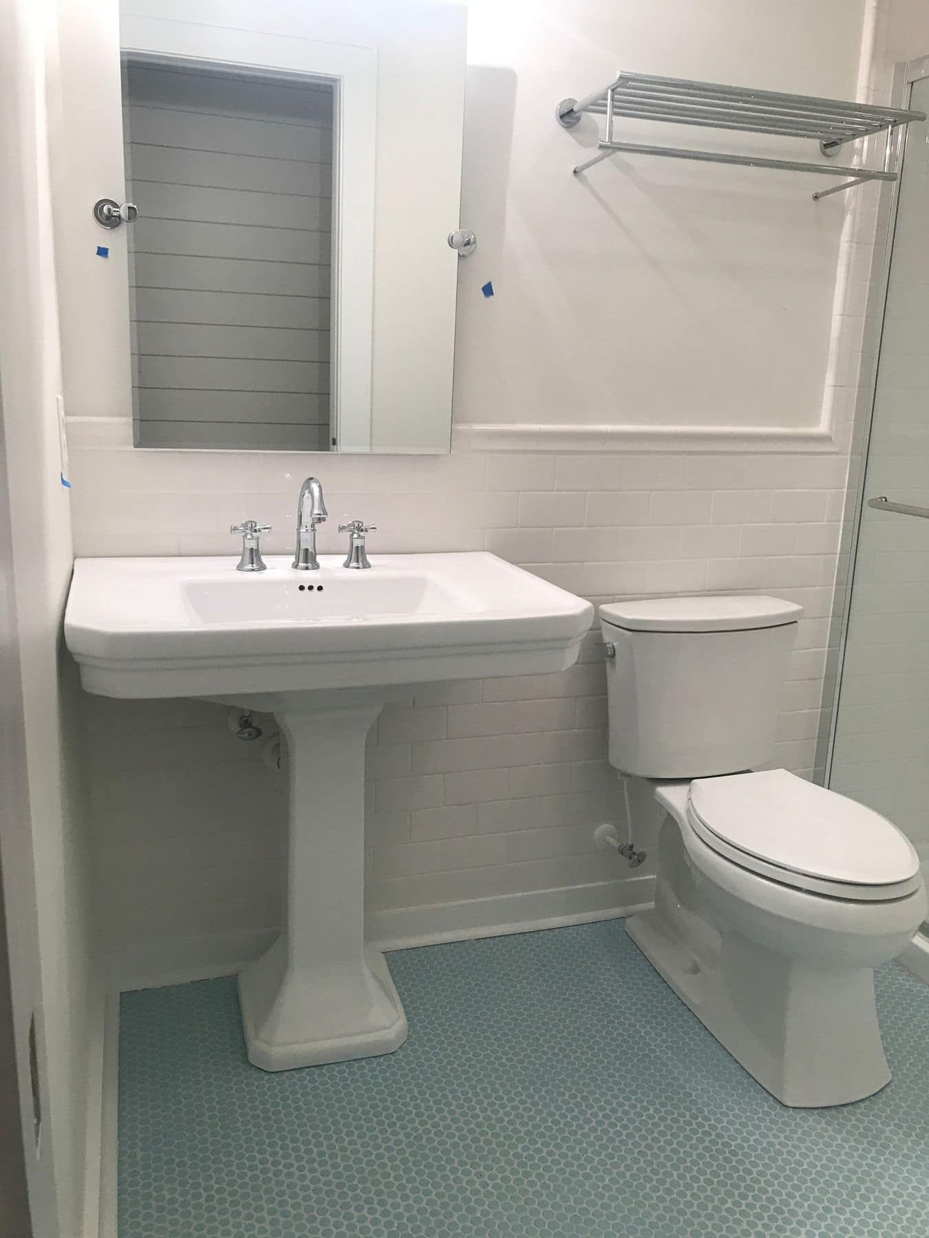 A bath with a pedestal sink and aqua hex tile floor