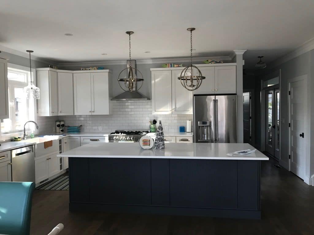 Kitchen with a navy island, white cabinets, and globe pendants