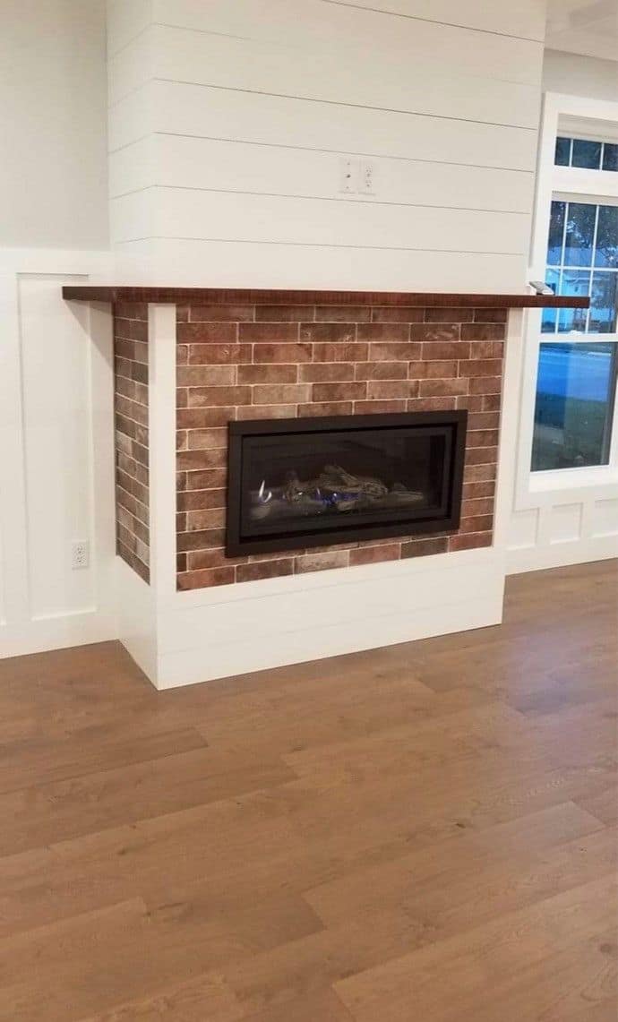 Gas fireplace with a brick surround and shiplap above