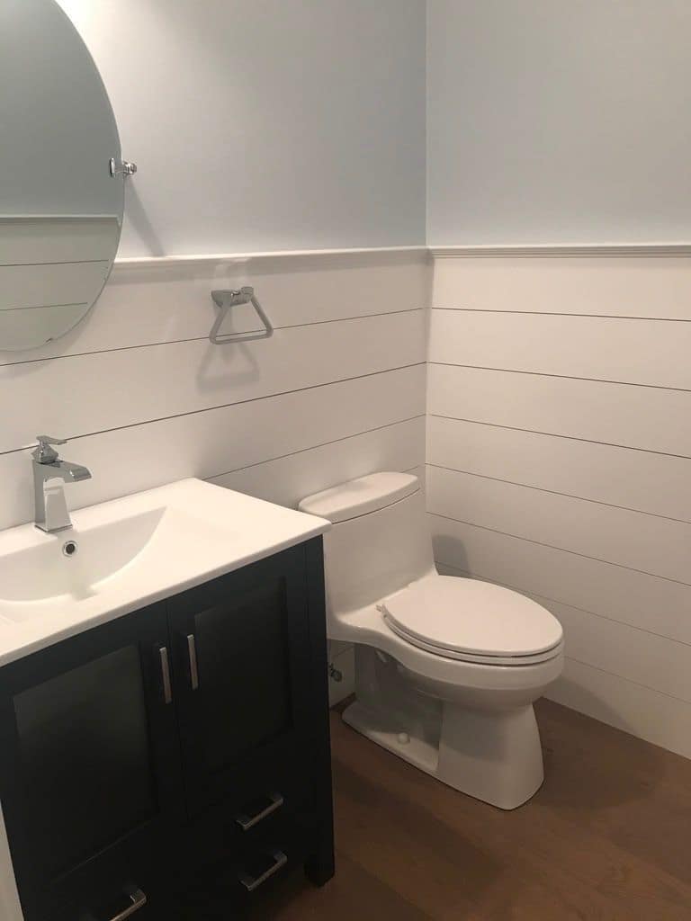 Powder room with shiplap walls and a navy vanity