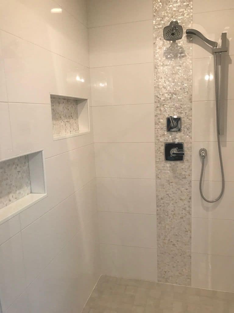 Tiled shower with a pebble accent strip and niches